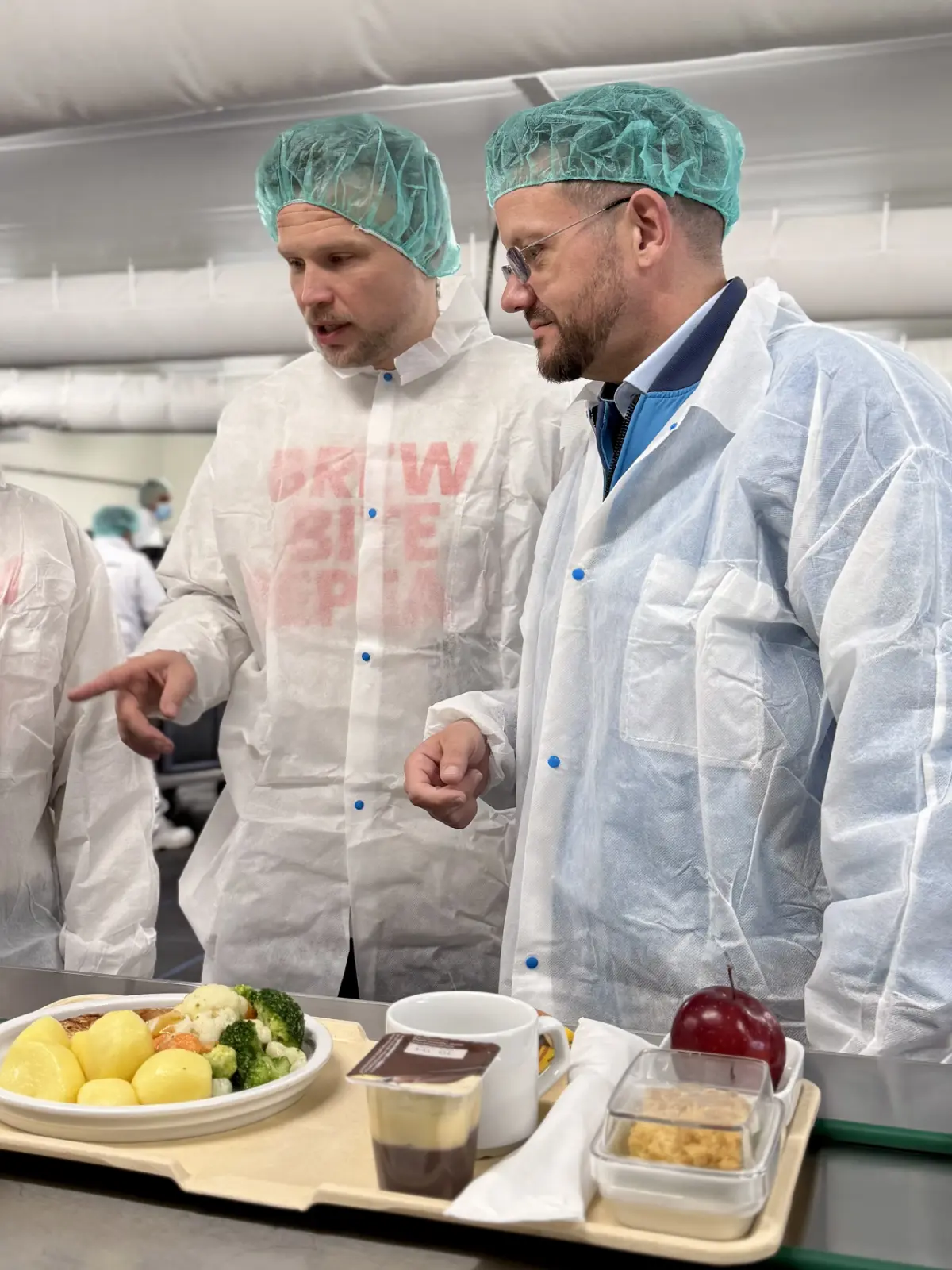 Tobias Grau mit Wojtek und Elvira am Tablettband der Vivantes-Küche